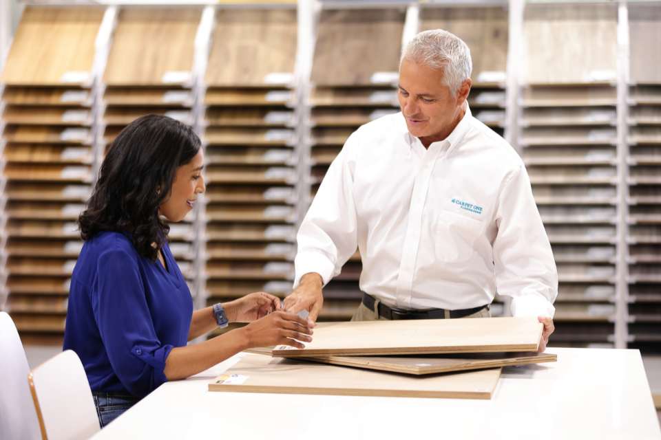 carpet one salesperson showing customer flooring sample